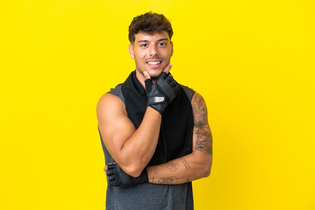 Young sport caucasian man with towel isolated on yellow background smiling