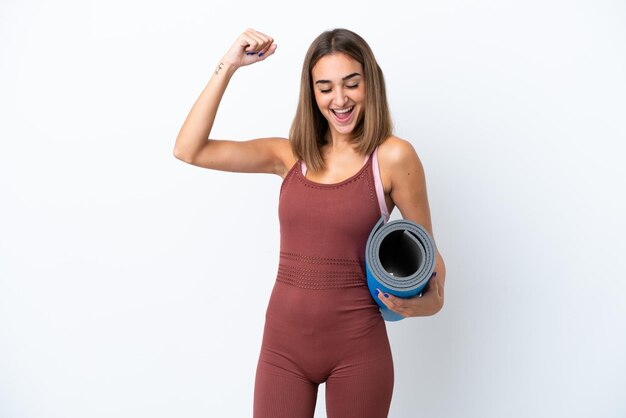 Young sport caucasian woman going to yoga classes isolated on white background celebrating a victory