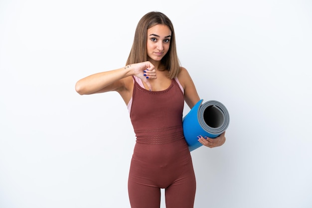 Young sport caucasian woman going to yoga classes isolated on white background showing thumb down with negative expression