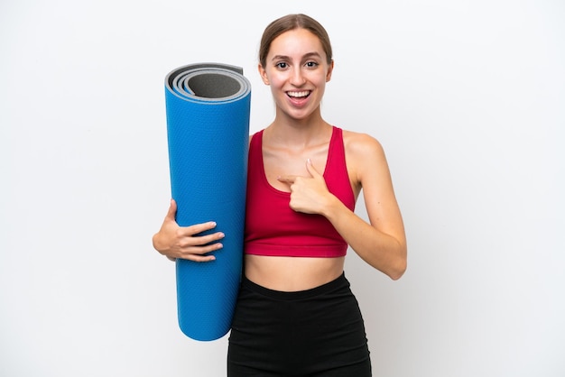 Young sport caucasian woman going to yoga classes while holding a mat isolated on white background with surprise facial expression