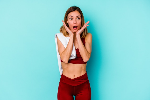 Young sport caucasian woman isolated on blue background surprised and shocked.