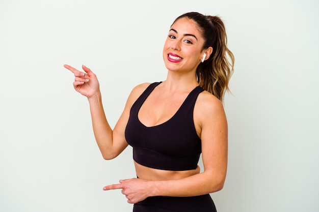 Young sport caucasian woman isolated on white background excited pointing with forefingers away.