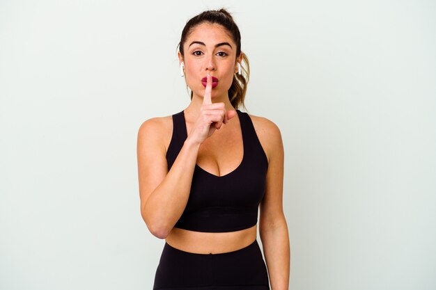 Young sport caucasian woman isolated on white background keeping a secret or asking for silence.