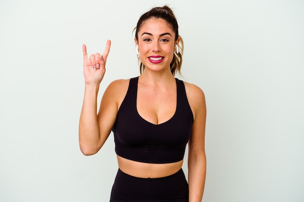 Young sport caucasian woman isolated on white background showing a horns gesture as a revolution concept.