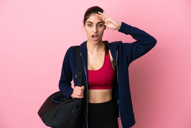 Photo young sport caucasian woman with sport bag isolated on pink background with surprise expression