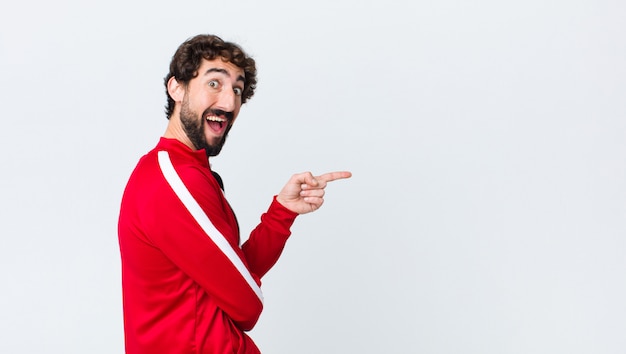 young sport dressed man surprised pointing to the side