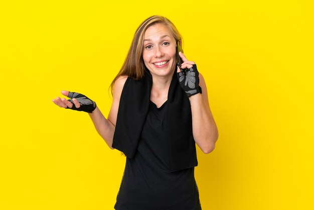 Young sport english woman isolated on white background keeping a conversation with the mobile phone with someone