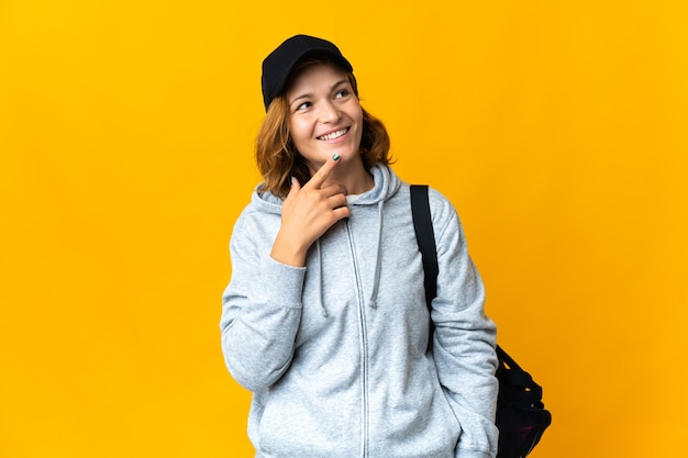 Young sport Georgian woman with sport bag over isolated wall looking up while smiling