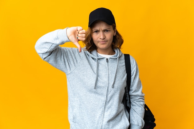 Young sport Georgian woman with sport bag over isolated wall showing thumb down with negative expression