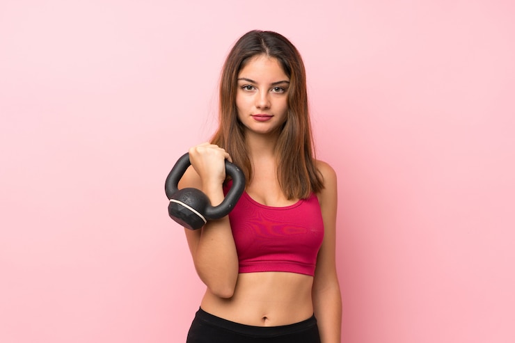 Photo young sport girl background making weightlifting with kettlebell and looking to the front