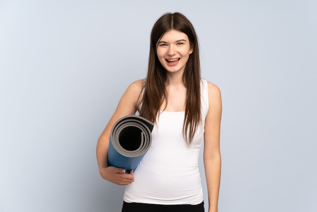 Young  sport girl going to yoga classes while holding a mat with surprise facial expression