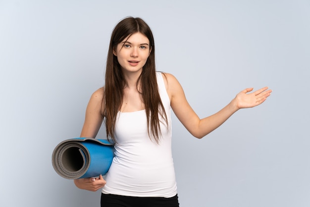 Young  sport girl going to yoga classes while holding a mat