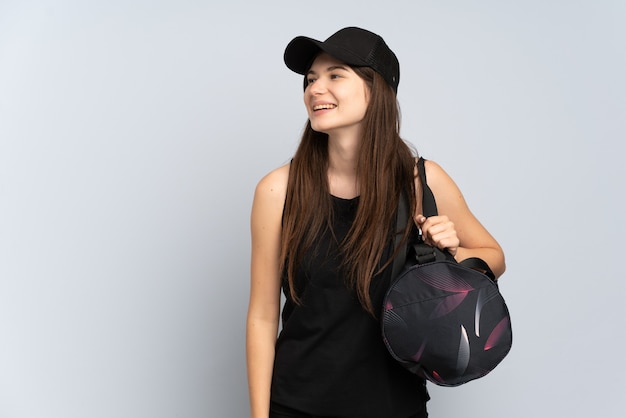 Foto ragazza giovane sport con borsa sportiva isolata su grigio che osserva al lato e sorridente
