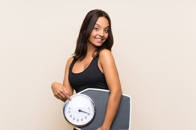 Young sport girl with weighing machine over isolated wall