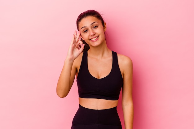 Young sport Indian woman isolated on pink cheerful and confident showing ok gesture.