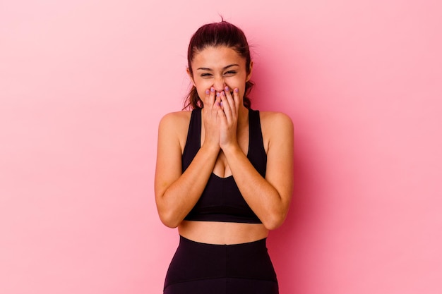 Young sport Indian woman isolated on pink laughing about something, covering mouth with hands.