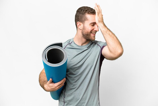 Young sport man going to yoga classes while holding a mat over isolated white background has realized something and intending the solution