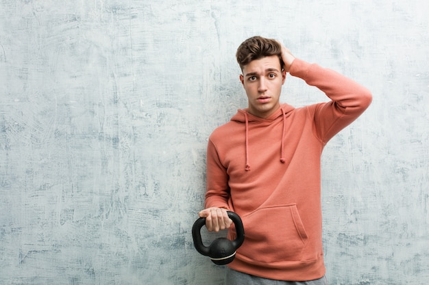 Young sport man holding a dumbbell being shocked, she has remembered important meeting.