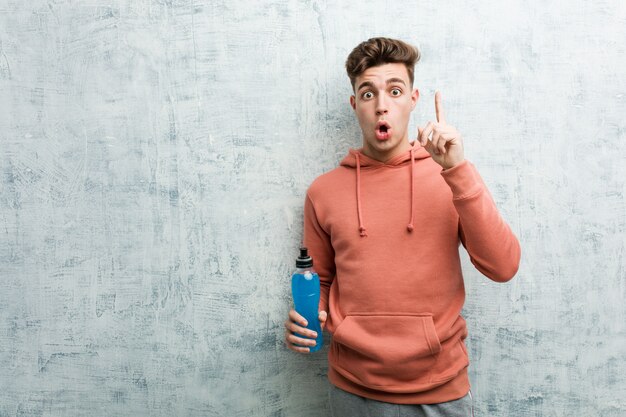 Young sport man holding an energy drink having some great idea