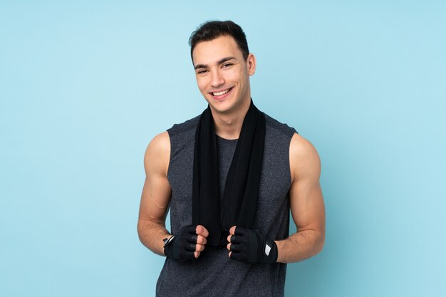 Young sport man over isolated on blue wall with sport towel