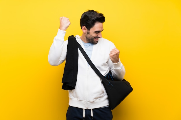 Young sport man over isolated yellow wall celebrating a victory