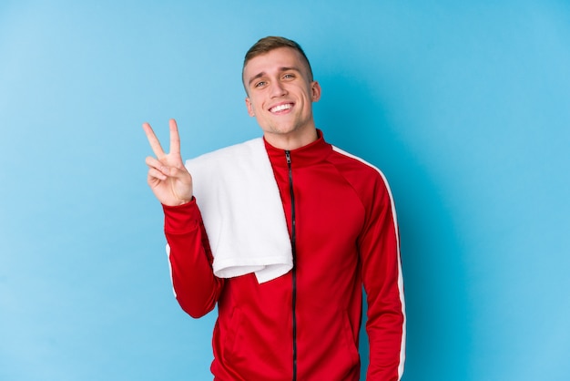 Young sport man joyful and carefree showing a peace symbol with fingers.