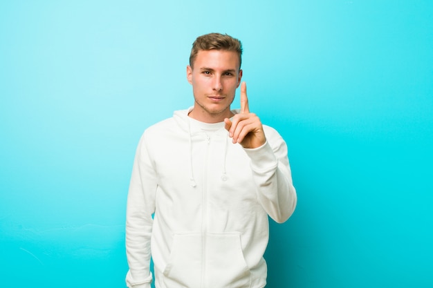 Young sport man showing number one with finger