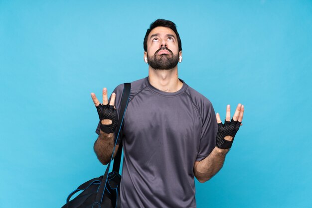 Young sport man with beard over isolated blue frustrated by a bad situation