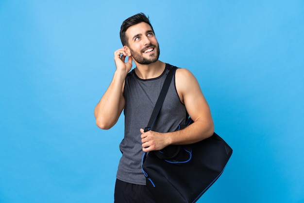 Young sport man with sport bag isolated on blue background thinking an idea