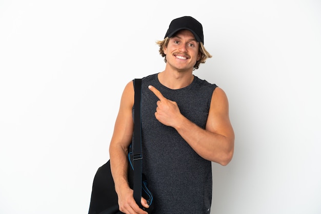 Young sport man with sport bag isolated on white pointing to the side to present a product