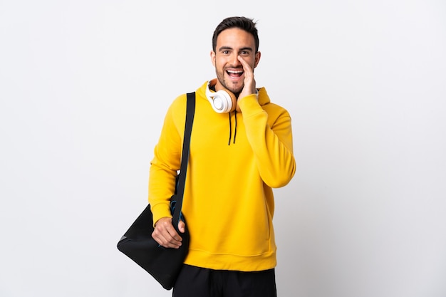 Young sport man with sport bag isolated on white  shouting with mouth wide open