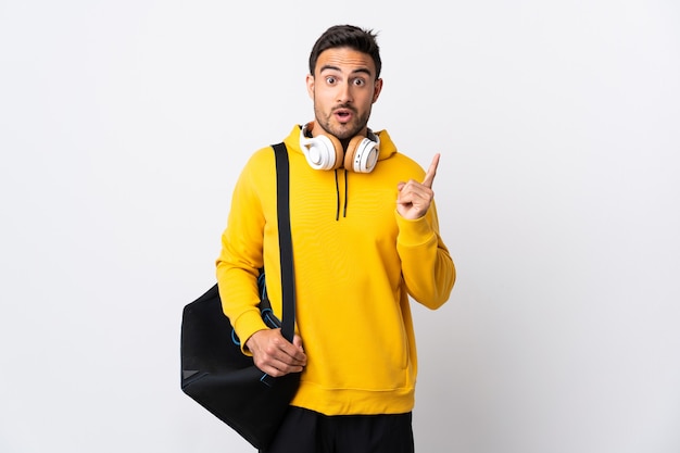 Young sport man with sport bag isolated on white wall intending to realizes the solution while lifting a finger up