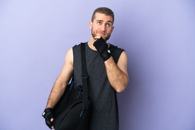 Young sport man with sport bag isolated on white wall and looking up