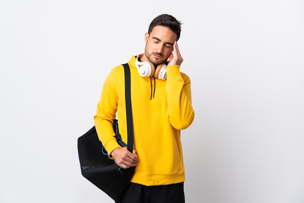 Young sport man with sport bag isolated on white wall with headache