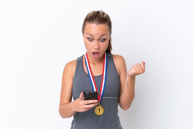 Young sport Russian girl with medals isolated on white background surprised and sending a message