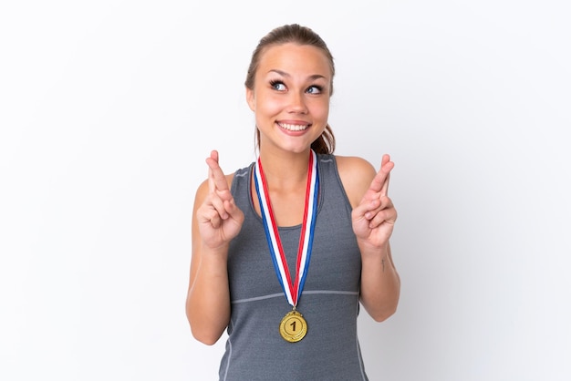 Young sport Russian girl with medals isolated on white background with fingers crossing