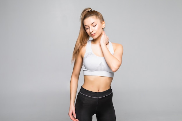 Young sport woman in a fitness outfit experiencing neck isolated