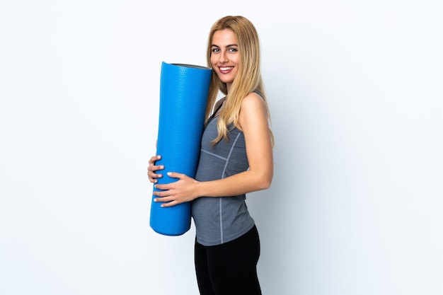 Young sport woman going to yoga classes while holding a mat over isolated white