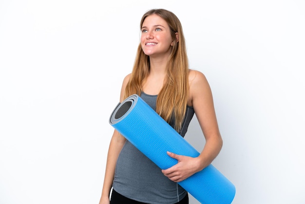 Young sport woman going to yoga classes while holding a mat thinking an idea while looking up