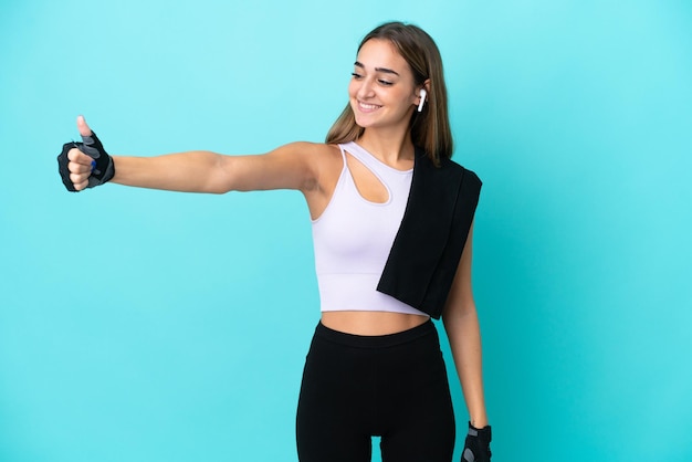 Young sport woman isolated on blue background giving a thumbs up gesture