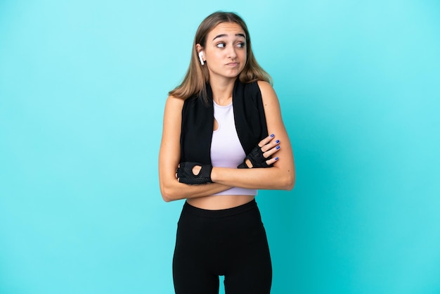 Young sport woman isolated on blue background making doubts gesture while lifting the shoulders