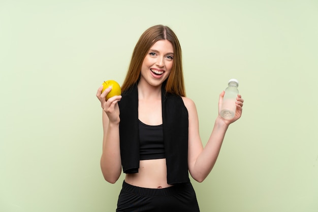 Young sport woman over isolated green with an apple