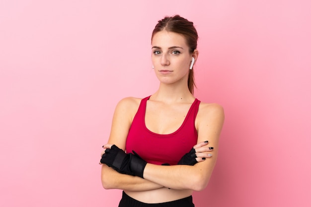 Young sport woman over isolated pink wall keeping the arms crossed