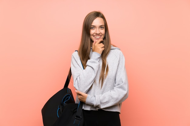 Young sport woman over isolated pink wall laughing