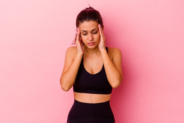 Young sport woman isolated on pink wall touching temples and having headache