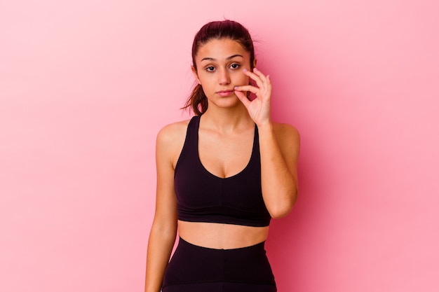 Young sport woman isolated on pink wall with fingers on lips keeping a secret