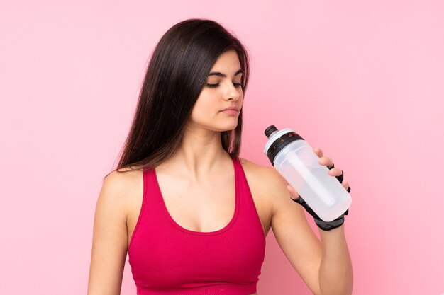 Young sport woman over isolated pink with sports water bottle