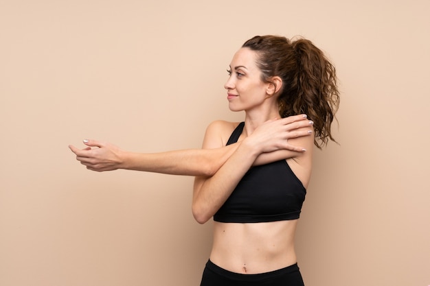 Foto giovane donna di sport sopra la parete isolata che allunga braccio