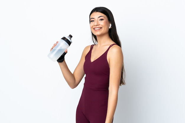 Young sport woman over isolated white wall with sports water bottle