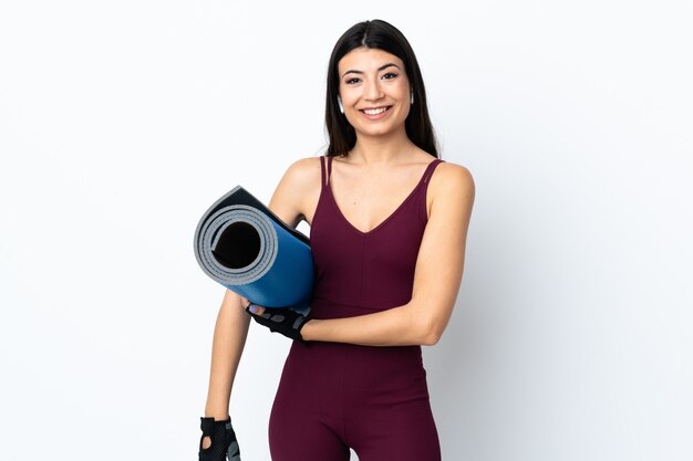 Young sport woman over isolated white with a mat and smiling